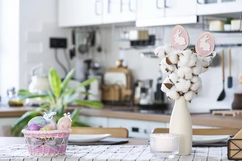 Easter decoration of colorful eggs in a basket and a rabbit on the kitchen table Foto stock