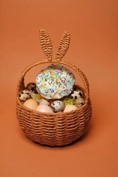 Easter decorations in a basket with rabbit ears. Easter cake and eggs on mo.. Stock Photos