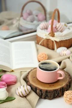 Easter decorations. Cup of coffee, painted eggs, tulips and book on windowsil Stock Photos