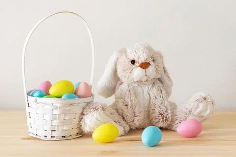 Easter decorations. Easter toy bunny, colored eggs in basket on the table. Stock Photos