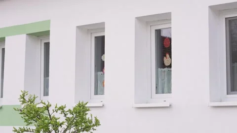 Easter decorations hanging in a kindergarten window on a white building facade Видео 339754698