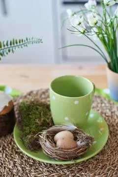 Easter decorations in the kitchen with eggs in a nest and a cup for tea 库存照片