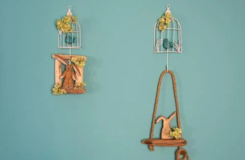 Easter decorations on the wall, a cage with a bird and bunnies. Stock Photos