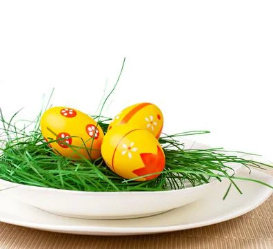 Easter decoration.Three easter eggs with a green decoration on a plate 스톡 사진