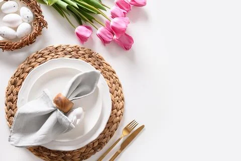Easter dinner with eggs, bunny, festive tableware and tulips on white. Stock Photos