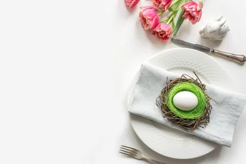 Easter dinner. Table setting with pink tulip, eggs on white table. Top view. Stock Photos