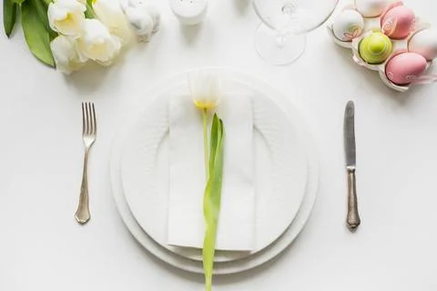 Easter dinner. Table setting with white tulip on white table. Top view. Stock Photos