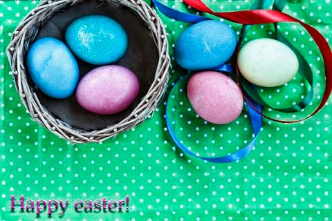 Easter. Easter eggs in a basket on a green background and colored ribbons. Ha Photos