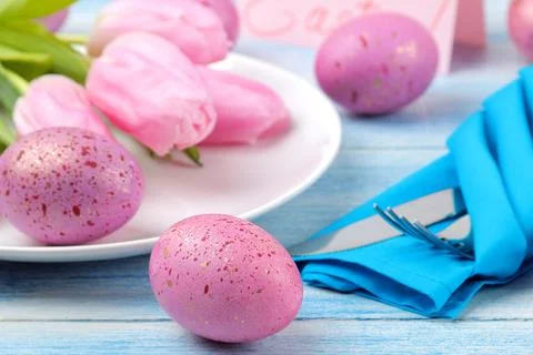 Easter. Easter table setting. Pink easter eggs and flowers tulips on a blue w Foto stock