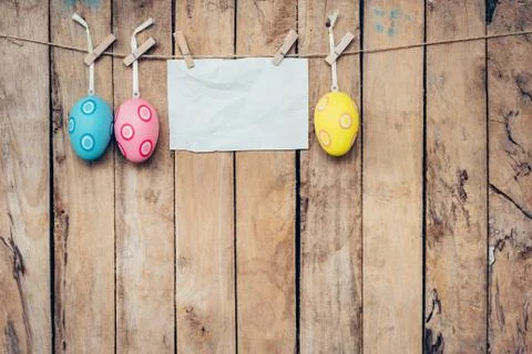 Easter egg and blank paper for label hanging on wood background with space. Stock Photos