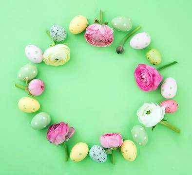 Easter egg and Spring flowers decoration wreath on green pastel background, t Stock Photos