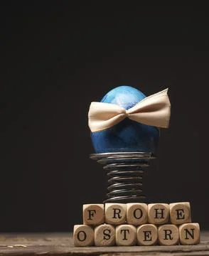 Easter egg with a bow on an old rustic wooden table, wooden dices with the Foto stock