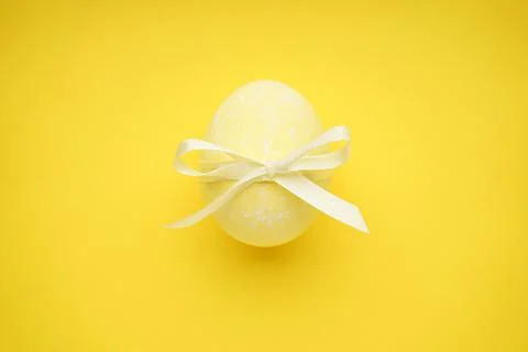Easter egg with a bow on a yellow background. Top view Foto stock