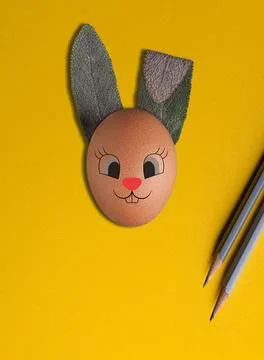 Easter egg bunny with ears made from fresh sage andpencils on yellow background. Stock Photos
