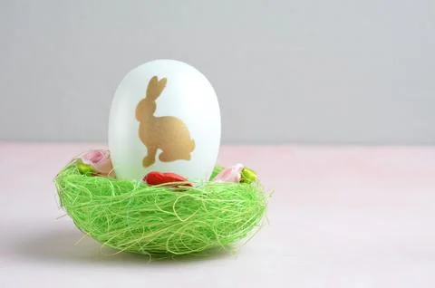Easter egg with a bunny pattern in a green basket. Pink background. Easter. 스톡 사진