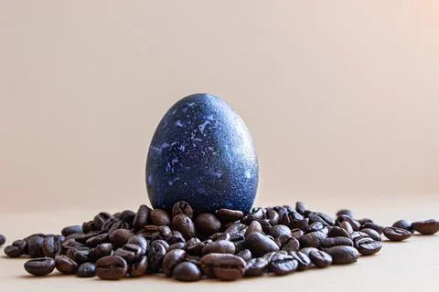 Easter egg in coffee beans. The egg is blue. On a light background Stock Photos