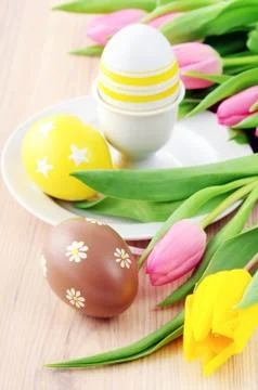 Easter egg in cup with bunch of tulips around Stock Photos