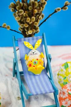 Easter egg in deck chair, blue background, holiday on easter Stock Photos