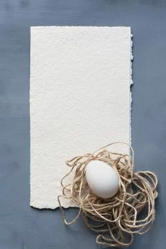 Easter egg decorated with twine in the shape of a nest on a gray textured bac Stock Photos