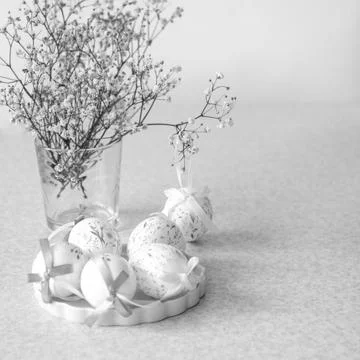 Easter egg decoration with floral pattern and ribbon beside vase of delicate Foto stock
