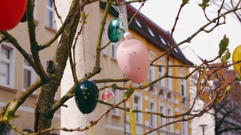 Easter egg decorations on a tree on a street lined with apartments in a city Vídeos de archivo 332682407