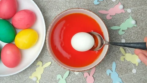 Easter egg dyeing process, egg placed in dye, slow motion, top view Stock Footage 300089737