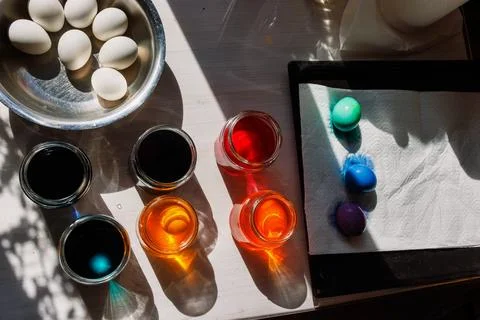 Easter egg dyeing setup with color jars and dyed eggs on tray. Top view Stock Photos