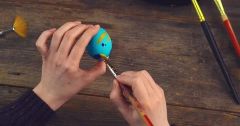 Easter egg in female artist's hands. Close up top view video of woman painting Stock Footage 150960627