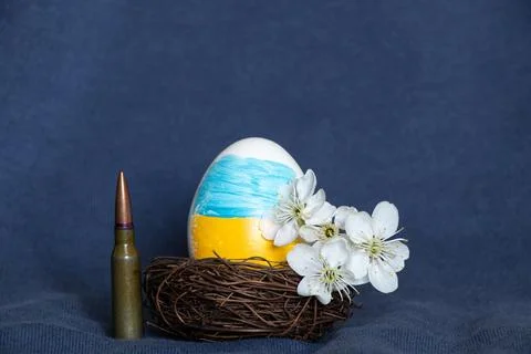 Easter egg with the flag of Ukraine, a flowering branch and a bullet on a b.. Stock Photos