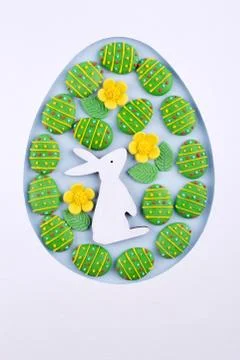 Easter egg frame made of paper, sugar candy eggs, bunny on blue background Stock Photos