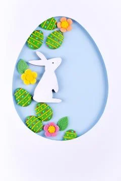 Easter egg frame made of paper, sugar candy eggs, bunny on blue background Stock Photos
