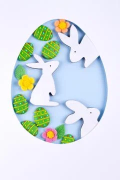 Easter egg frame made of paper, sugar candy eggs, bunny on blue background Stock Photos