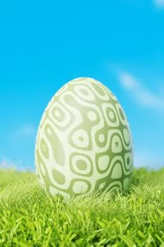 Easter egg in the grass in the meadow. Green Easter egg with patterns in th.. Ilustración de archivo