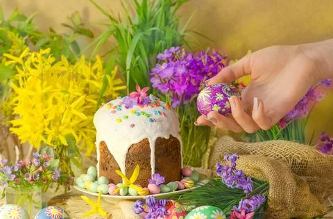 Easter egg in a hand on a background of Easter decoration and spring flowers. Stock Photos