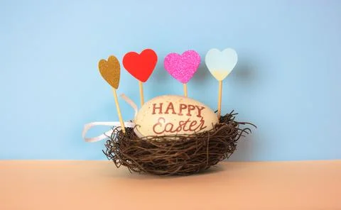 Easter egg with Happy Easter text in a nest on a delicate blue background. Stock-Fotos
