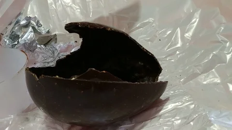 An Easter egg has been opened, the broken chocolate shell is on the table Stock Footage 106887933