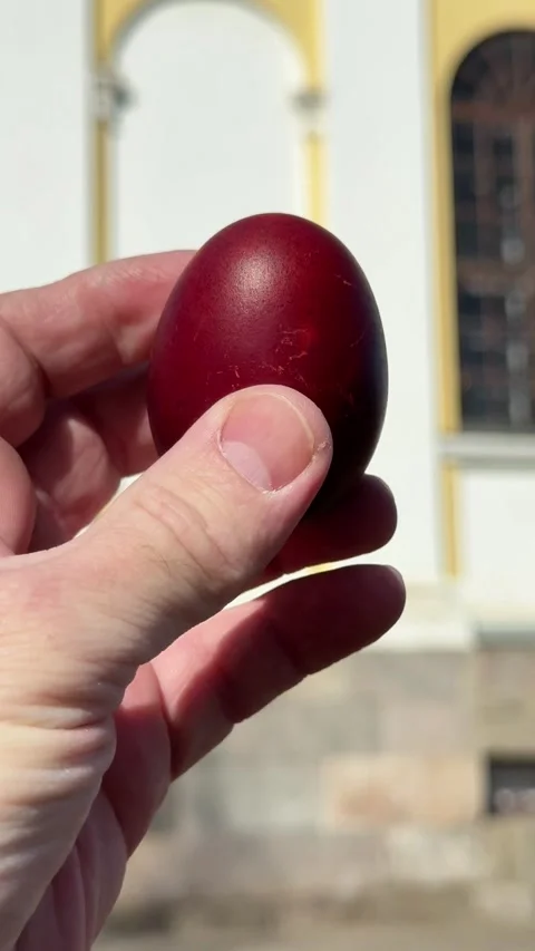 Easter egg held in hand against a soft blurred church background Stock Footage 332736140