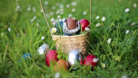 Easter Egg Hunt. Chocolate Easter Eggs in a round basket on a green clover Stock Footage 237727166