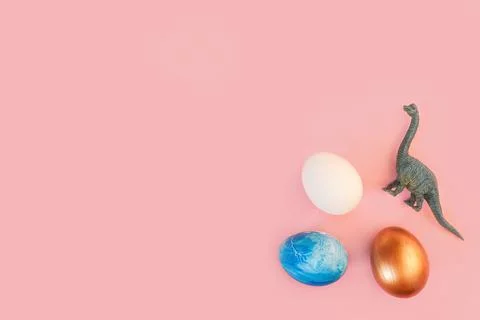 Easter egg hunt holiday composition, colorful eggs with dinosaur on light pastel Stock Photos