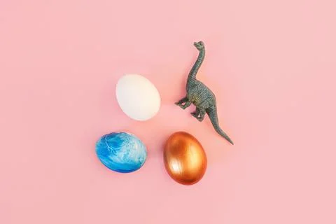 Easter egg hunt holiday composition, colorful eggs with dinosaur on light pastel Stock Photos