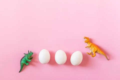 Easter egg hunt holiday composition, white eggs with dinosaur on light pastel Photos