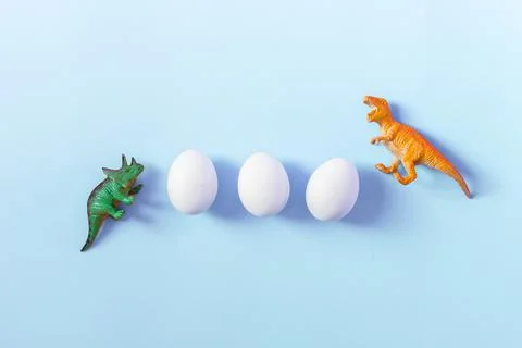 Easter egg hunt holiday composition, white eggs with coloful dinosaur on light Stock Photos