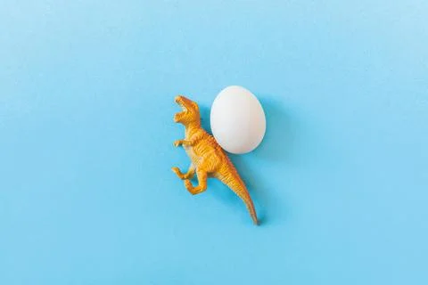 Easter egg hunt holiday composition, white eggs with dinosaur on light blue Stock Photos