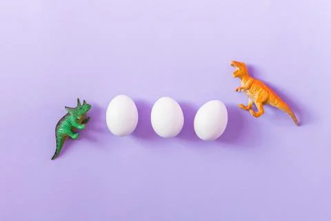 Easter egg hunt holiday composition, white eggs with dinosaur on pastel violet Stock Photos