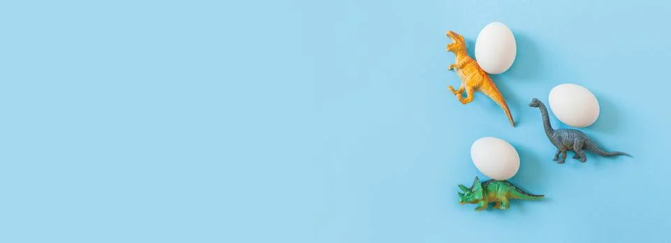 Easter egg hunt holiday composition, white eggs with coloful dinosaur on light Stock Photos
