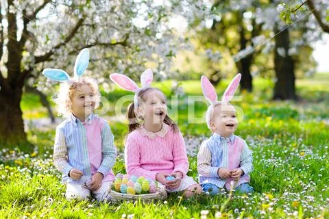 Easter egg hunt. Kids with bunny ears and basket. Stock Photos