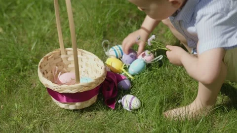 Easter Egg Hunt tradition: kid boy picking up colorful eggs from green grass put Stock Footage 233124633