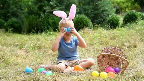 Easter egg hunt.Little boy child kid in bunny ears having fun,picking up eggs in Stock Footage 330937305