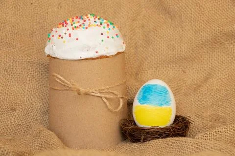 Easter egg with the image of the flag of Ukraine in the nest and Easter cake  Stock Photos