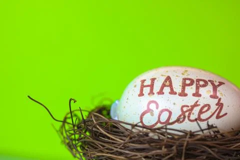 An Easter egg with a inscription Happy Easter in a bird's nest, green backgrond Stock Photos